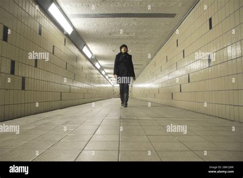 Young Adult Woman Walking Through Underground Pedestrian Tunnel Stock