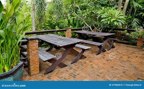 Wooden Chairs And Table Set At Balcony In A Green Plant Garden Stock