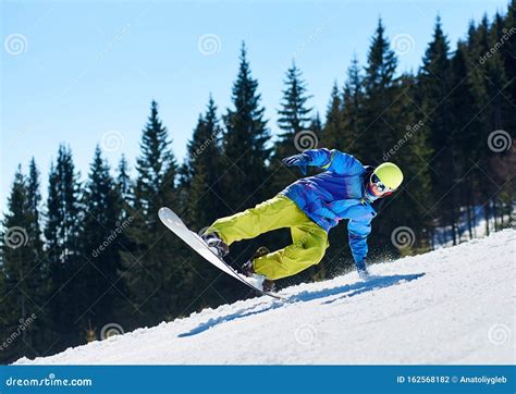 Snowboarder Riding Snowboard Down Snowy Mountain Slope On Sunny Winter