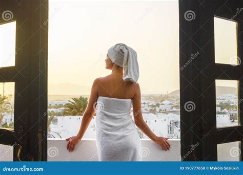 Back View Of Pretty Girl On A Balcony Wrapped In White Towel After Having A Bath Woman Is