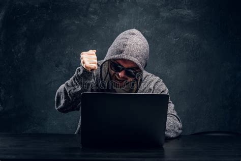 Hacker In Hoodie And Sunglasses Holds A Knife Lock Up Sitting Behind A