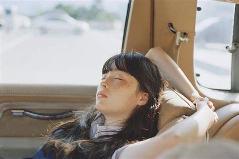 A Woman Sitting In The Back Seat Of A Car With Her Eyes Closed Looking