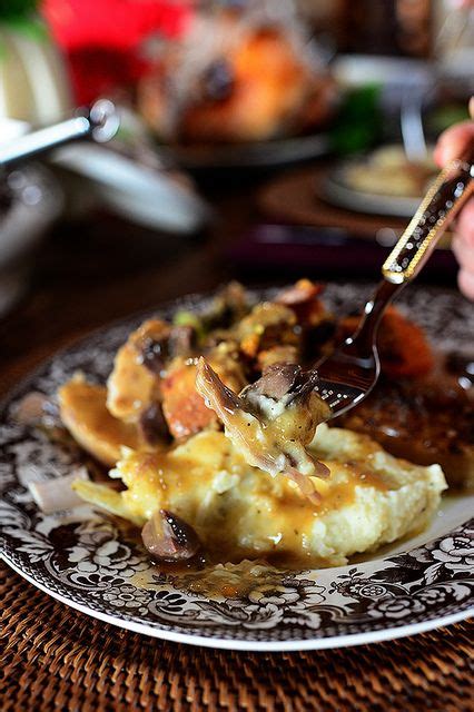 A Person Is Eating Mashed Potatoes With Gravy On A Plate At A Table