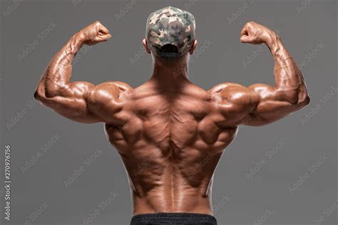 Rear View Muscular Man Showing Back Muscles And Biceps Isolated On The Gray Background Strong