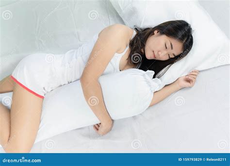 Asian Woman Lying And Sleep On The Bed Hugging Bolster Stock Image
