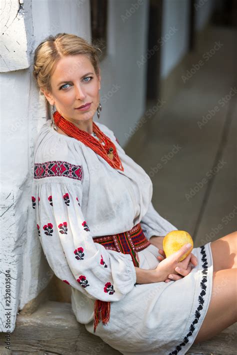 ukrainian girl sits near the village house in embroidered dress in the village portrait of