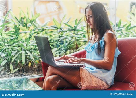 Portrait Of Young Female Freelancer Working On Laptop Sitting In Cafe