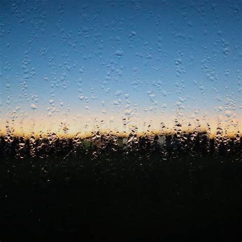 Glass Covered In Morning Dew With A View Of A Blurry Sunrise Stock