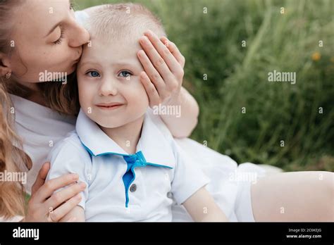 Madre Besando A Su Hijo Pequeño Con Ojos Azules Al Fondo Del Campo