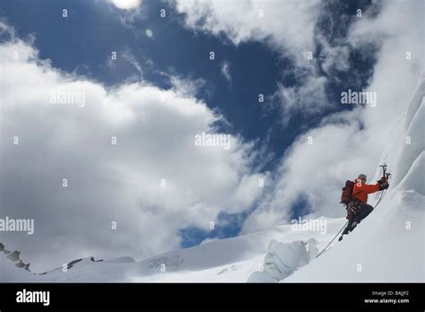 Mountain Climber Going Up Snowy Slope With Axes Stock Photo Alamy