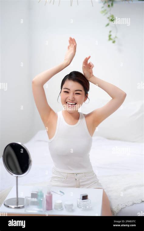 Slim Young Woman Shows Tender Smooth Armpit Skin In Bedroom Stock Photo