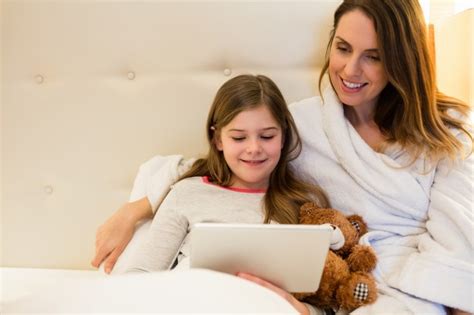 Madre E Hija Que Usa La Tableta Digital En El Dormitorio
