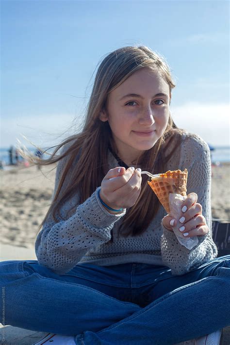 Teen Girl Eating A Waffle Cone Filled With Ice Cream At The Beach By
