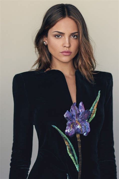A Woman In A Black Dress With A Purple Flower On Her Lapel And Long Sleeves