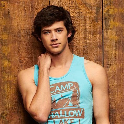 A Young Man In A Tank Top Leaning Against A Wooden Wall With His Hand
