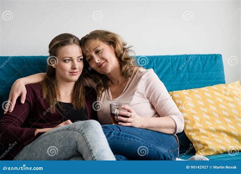 Madre E Hija Adolescente Que Abrazan En El Sofá En Casa Imagen De