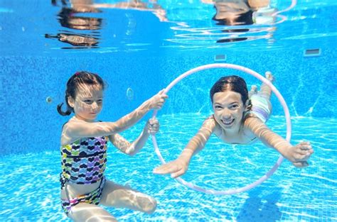 Дети плавают в бассейне под водой счастливые активные девочки