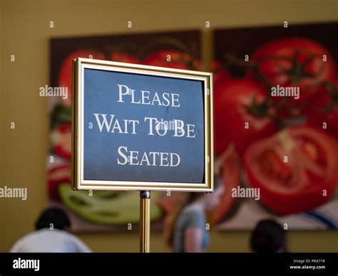 Please Wait To Be Seated Sign Standing At The Front Of A Restaurant