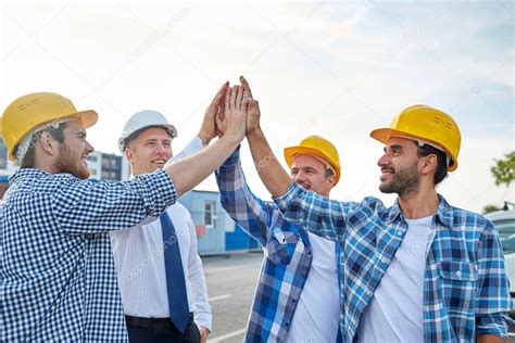 Close Up Of Builders In Hardhats Making High Five Stock Photo By ©syda