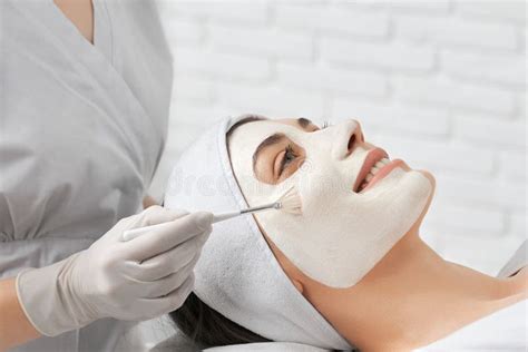 Smiling Young Woman Doing Procedure For Face In Beautician Stock Photo