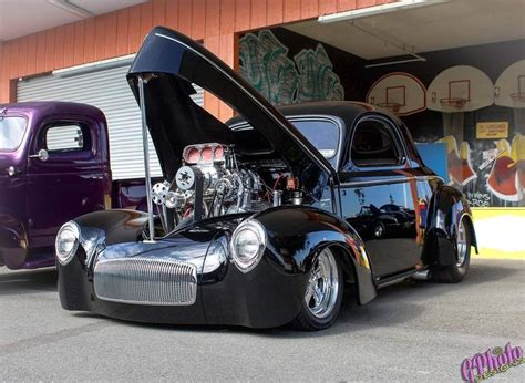 an antique car with the hood open parked in front of a building next to