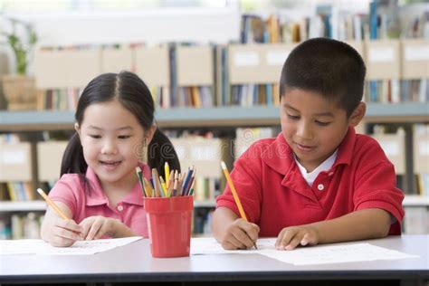 Children Sitting At Desk And Writing In Classroom Stock Image Image