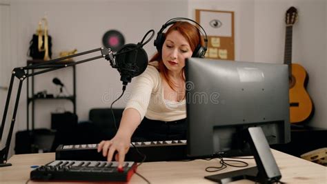 Young Redhead Woman Musician Playing Piano Keyboard At Music Studio