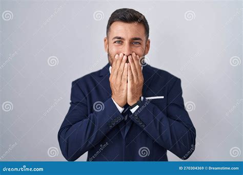 Handsome Hispanic Man Wearing Suit And Tie Laughing And Embarrassed Giggle Covering Mouth With