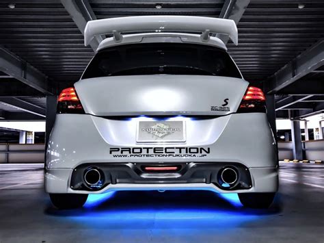 the back end of a white car in a parking garage with blue lights on it