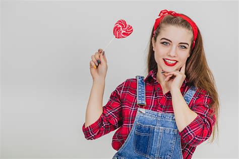 Stylish Lovely Enticing Girl Raising Up The Red Heartshape Lollypop On The Stick Looking Lovely