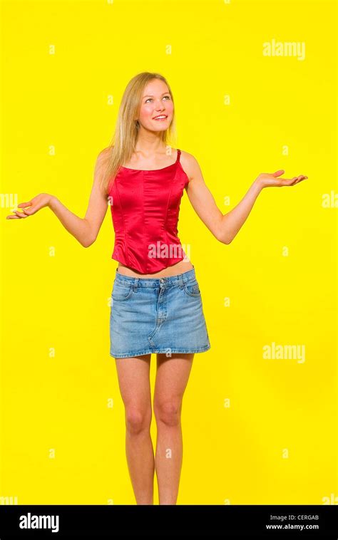 Female Blonde Hair Denim Mini Skirt Red Satin Corset Style Top Standing With Arms Up Aldo