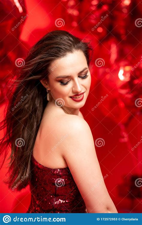 Beautiful Young Woman In Red Evening Dress Posing Over Red Background With Big Heart Shape