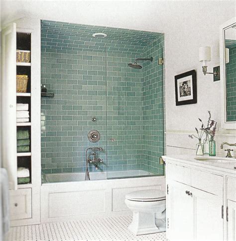 A Bathroom With Green Tile And White Fixtures Including A Shower Stall