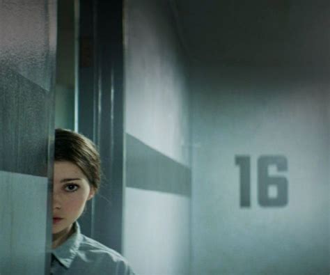 A Woman Standing Behind A Wall With The Number 16 On It