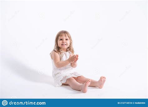 Belle Petite Fille En Robe Blanche Assise Sur Fond Blanc Photo Stock