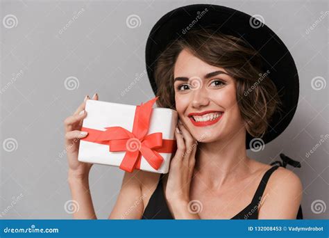 Photo Of Happy Woman 20s Wearing Black Dress And Hat Holding Present Box Isolated Over Gray