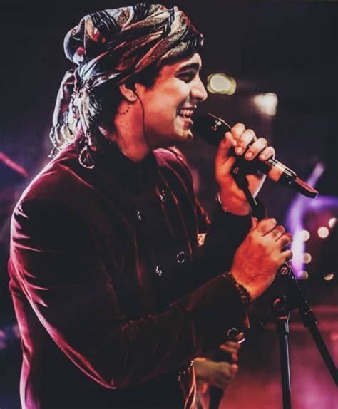 A Man With Dreadlocks On His Head Holding A Microphone In Front Of Him