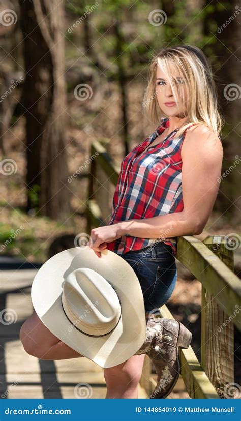 Cowgirl Resting On The Fence With Her White Cowgirl Hat Stock Image