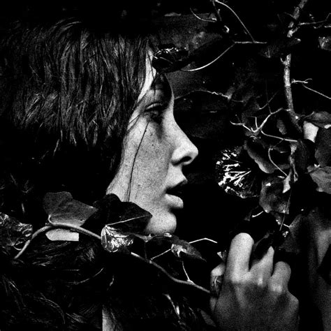 A Black And White Photo Of A Woman With Her Face Close To A Tree Branch