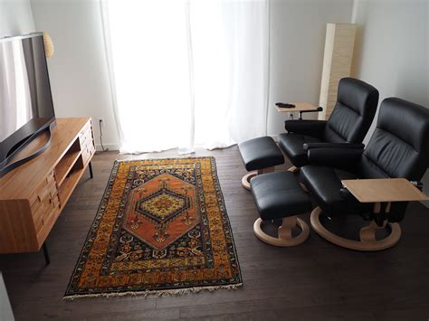 A Living Room With Black Leather Chairs And A Rug In Front Of A Tv On A