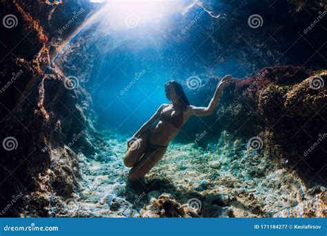 Woman In Bikini Posing Underwater Near Corals In Blue Ocean Stock