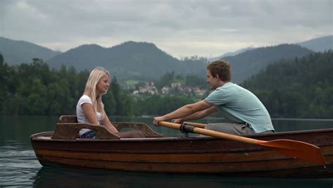 Teen Couple Rowing On Lake On Cloudy Warm Day In Slow