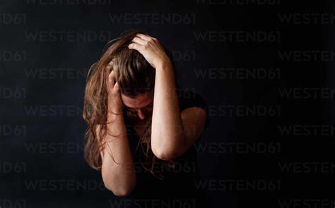 Distressed Woman With Long Brown Hair Holding Her Head In Her Hands Stock Photo