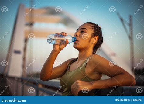 Sports Young Woman Standing On The Bridge And Drinking Water After