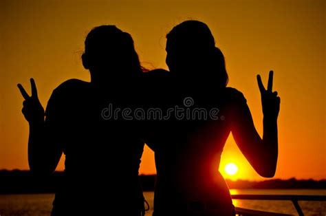 Two Teenage Girls Giving Peace Sign At Sunset Stock Photo Image Of