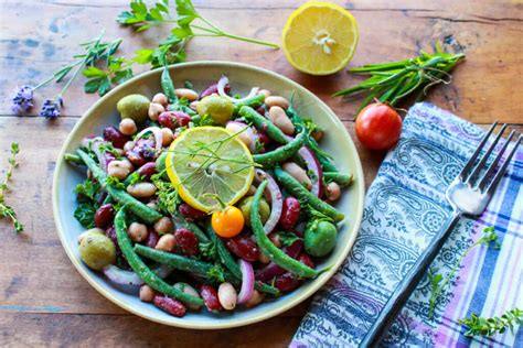 Four traditional falafel cakes on a bed of mixed greens, topped with red onion. Provencal Bean Salad - Sharon Palmer, The Plant Powered ...