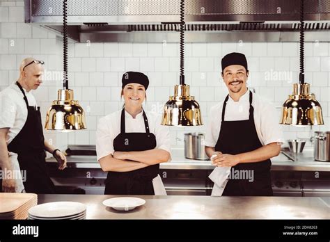 Portrait Of Happy Chefs Standing At Commercial Kitchen Counter Stock