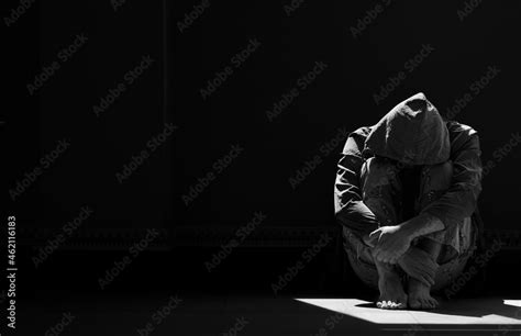 Light And Shadow On Surface Of Hopeless Man In Hoody Sitting Alone With