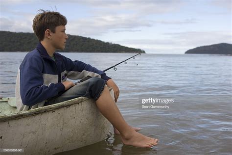 Boy Fishing From Boat Feet Hanging Over Side High Res Stock Photo