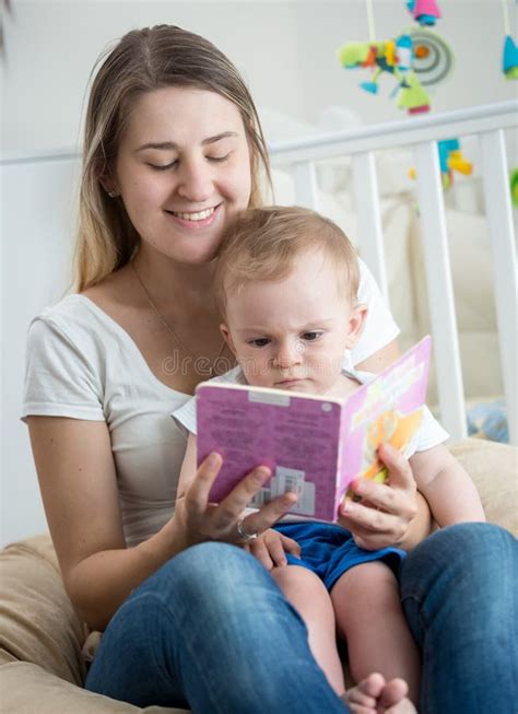 Portrait Of Happy Smiling Young Woman Reading Book To Her 10 Months Old